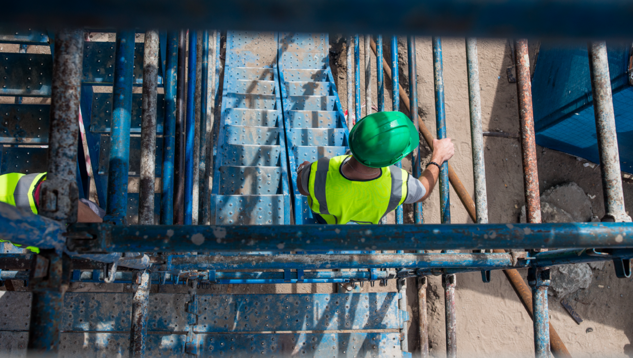 Homem com capacete de proteção descendo as escadas de uma estrutura em construção